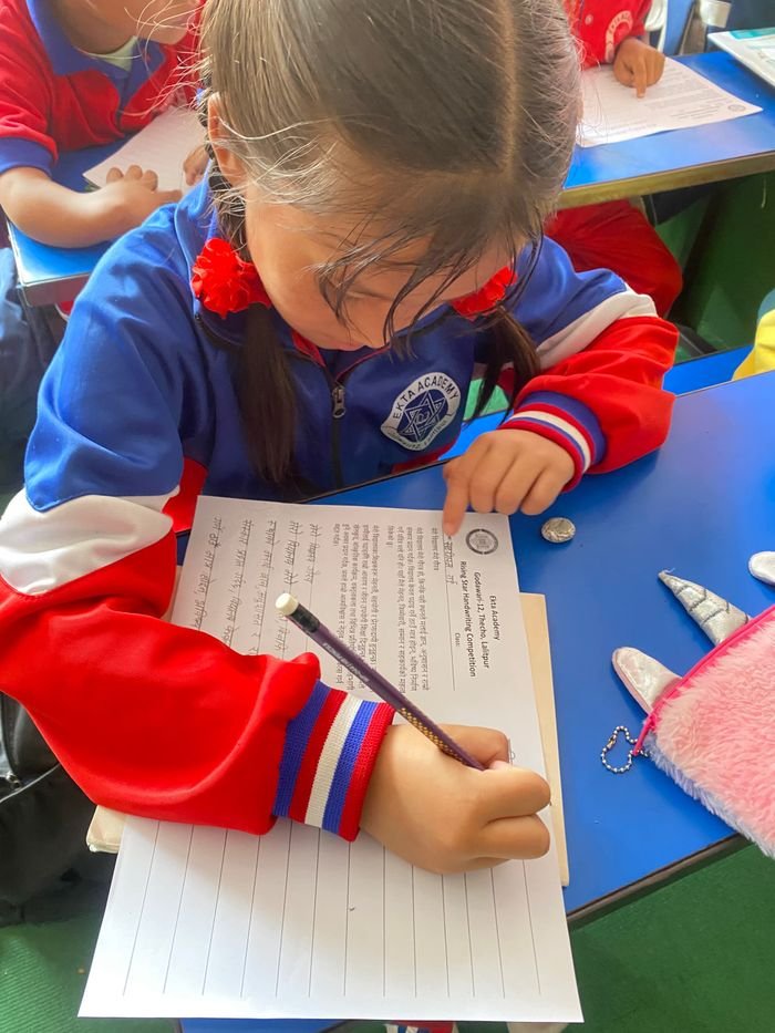A child focused on writing at a classroom desk.